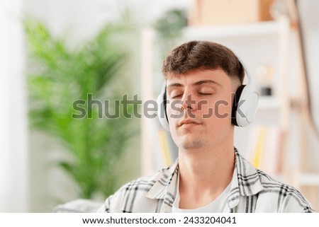 Closeup of young man meditating while listening relaxing music