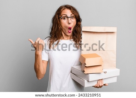 hispanic pretty woman looking astonished in disbelief. take away fast food packages concept