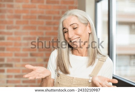 senior pretty woman holding an object with both hands on copy space, showing, offering or advertising an object