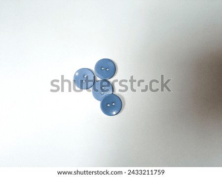 close-up of four blue sewing buttons isolated on a white background