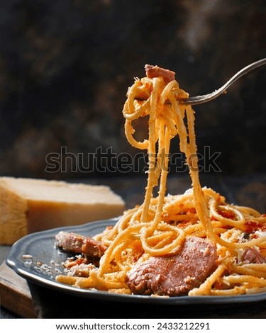 This is a picture of a delicious serving of spaghetti and meatballs garnished.The pasta dish is presented in a black bowl on a dark textured surface. 
