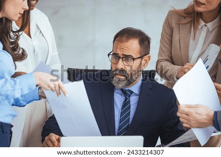 Mature businessman looking overwhelmed in a demanding work environment. Don't let the stress get the better of you. Shot of a mature businessman looking anxious in a demanding office environment Royalty-Free Stock Photo #2433214307