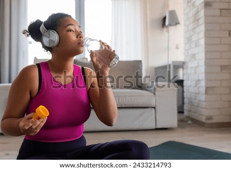 Woman resting after home workout, drinking water. New Year's resolutions, healthy lifestyle, losing weight and selfcare. Concept of morning or evening exercise. Royalty-Free Stock Photo #2433214793