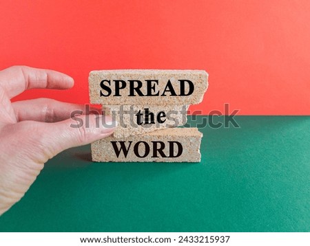 Spread the word symbol. Brick blocks with text Spread the word. Beautiful red background, green table, copy space. Businessman hand. Business, motivational concept.
