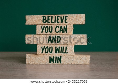 Motivational concept Believe You Can And You Will Win on brick blocks Beautiful green background, wooden table. Inspirational quotes for your design. Copy space. Royalty-Free Stock Photo #2433217053