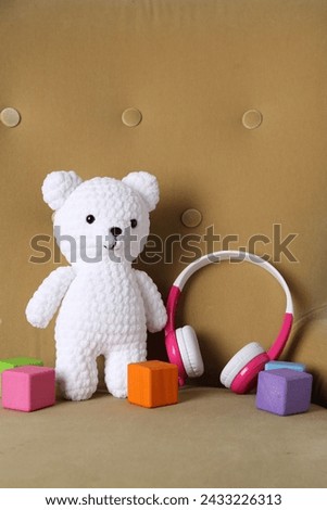 Baby songs. Toy bear, headphones and cubes on armchair
