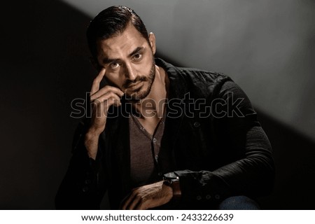 Handsome brutal macho guy posing on dark gray background, Young man's intense demeanor captured in a powerful, dark-themed portrait Royalty-Free Stock Photo #2433226639