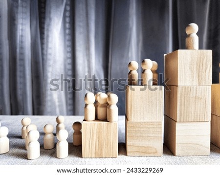 Wooden toy doll on high pedestal and many other figures below. Concept of leadership, which is not available to everyone. Victory and the winner. Talent, Recruitment employee and Successful business Royalty-Free Stock Photo #2433229269