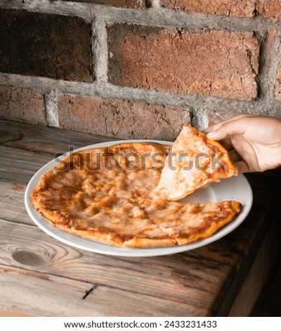 Whole pan of cheese pizza, with someone taking a slice out
