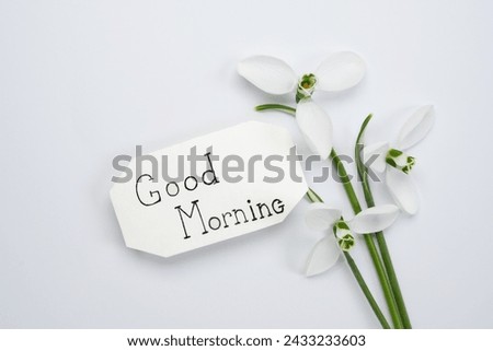Good morning calligraphy note with snowdrops bouquet on a white background. Top view, flat lay.