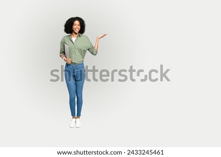 A cheerful African-American woman confidently presents with her hand, holding a tablet, against a clean white backdrop, ideal for overlaying text or graphics