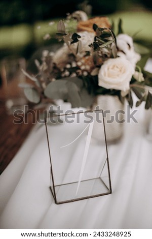 Many small pink and white flower arrangements with roses, eustoma and various flowers in clear glass vases. On the festive table in the wedding banquet area, compositions of flowers and greenery, cand Royalty-Free Stock Photo #2433248925