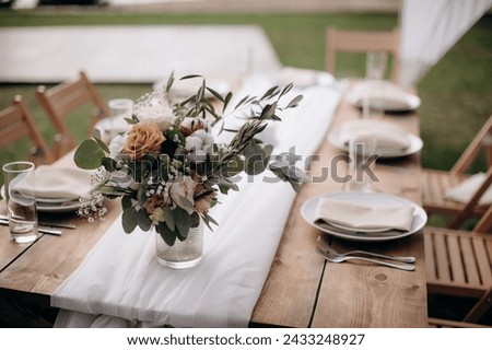 Many small pink and white flower arrangements with roses, eustoma and various flowers in clear glass vases. On the festive table in the wedding banquet area, compositions of flowers and greenery, cand Royalty-Free Stock Photo #2433248927