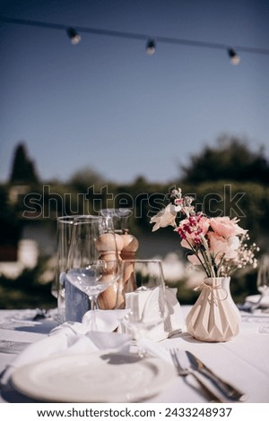 Many small pink and white flower arrangements with roses, eustoma and various flowers in clear glass vases. On the festive table in the wedding banquet area, compositions of flowers and greenery, cand Royalty-Free Stock Photo #2433248937