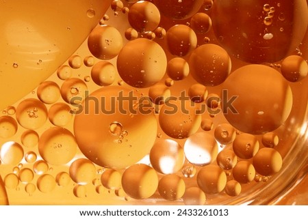 Yellow drops of oil or serum, and beer bubbles texture the background. Oil drops on the water's surface. Macro photography Royalty-Free Stock Photo #2433261013