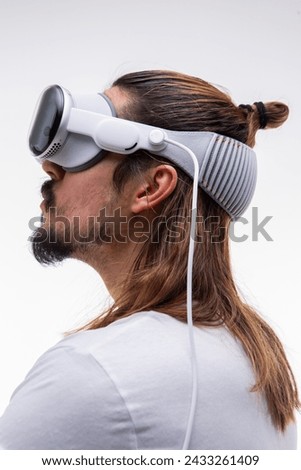 A man fully engaged in a spatial computing experience with a AR headset, reaching out to navigate the immersive digital environment. White background Royalty-Free Stock Photo #2433261409