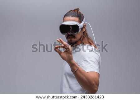 A young man engages with a virtual world using a mixed reality spacial computer headset, symbolizing cutting-edge technology in gaming and immersive digital experiences.  Royalty-Free Stock Photo #2433261423