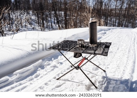 Folding Compact Camping Camping Table, Camping Utensils Stand Against Snow Background. High quality photo