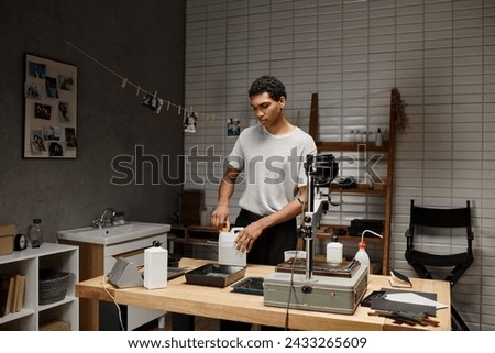 Serious young photographer engaged in analog film development in a professional darkroom setting