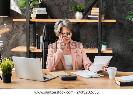 Sad stressed frustrated businesswoman ceo manager paying bills overdue, receiving pension report audit papers, loan mortgage banking debt in office Royalty-Free Stock Photo #2433282635