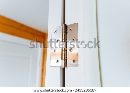 A close up of a wood door hinge on a white door, showcasing the hardwood plank and varnish finish. The parallel lines of the wood grain add a touch of sophistication to the rectangular design Royalty-Free Stock Photo #2433285189