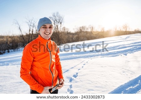 Man smiling standing against the background of snow, glare of the sun shining on the horizon, happy man in winter forest. High quality photo
