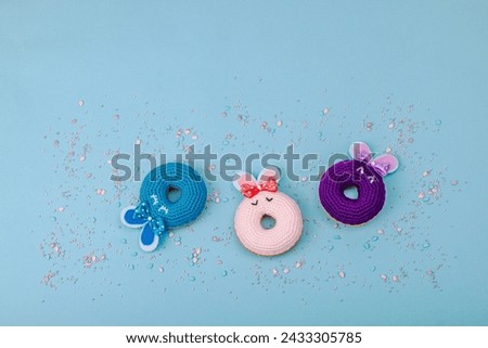 Handmade Easter concept. Crocheted donuts bunnies with traditional decoration. Festive symbols, greeting card, flat lay. Creative craft concept, pastel blue background, top view
