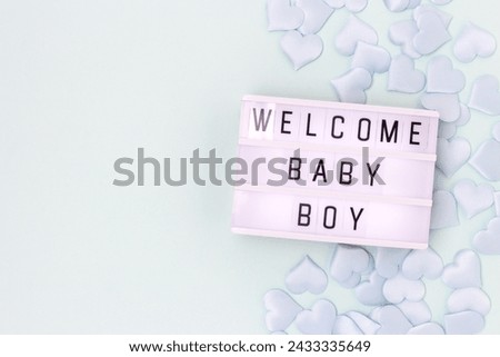 Welcome baby boy. Lightbox with letters and confetti in a heart shape on a blue background with place for text.