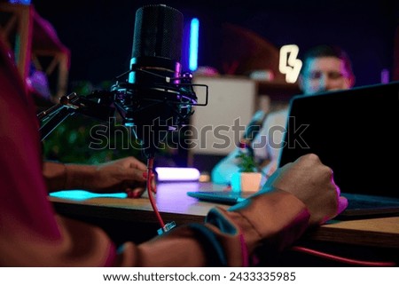 Focus on female hands, microphone and laptop. Blogger making online podcast show, discussing interesting lifestyle topics. Concept of online communication, modern technology, mass media