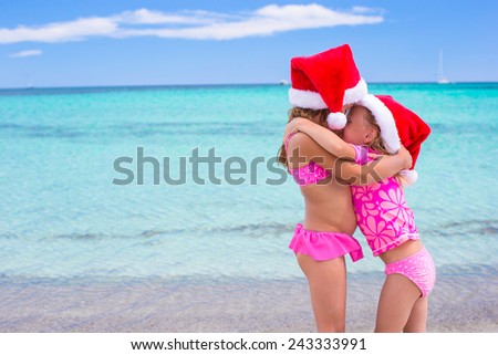 Little adorable girls in Santa hats during beach vacation