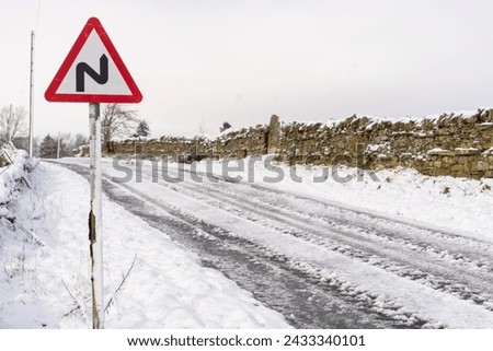 Road sign for bends ahead on a snow covered country road