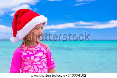 Little adorable girl wearing Santa hat at tropical beach