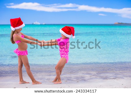 Little cute girls in Santa hats during summer vacation