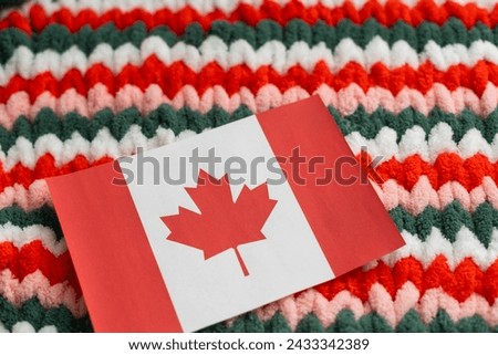 beautiful national flag of the country of Canada on a soft background texture of knitted wool with small fleeces of linen