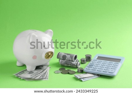 Financial savings. Piggy bank, dollar banknotes, coins and calculator on green background