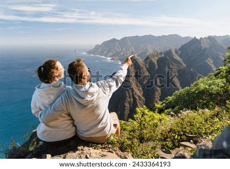 Hikers watching beautiful coastal scenery. Couple of traveler in love enjoying vacation in nature. Tenerife, Canary Islands, Anaga Rural Park, Spain. Travel, Outdoors and Lifestyle Concept.