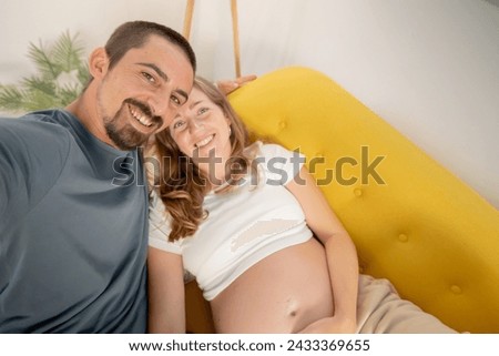 A pregnant woman and her husband are photographing themselves on the cell phone at home. High quality photo Royalty-Free Stock Photo #2433369655