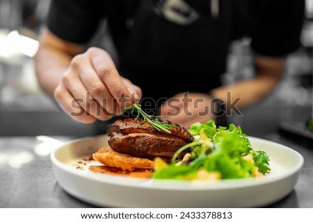A skilled chef artfully garnishes a perfectly grilled steak with fresh herbs, elegantly plated on white porcelain