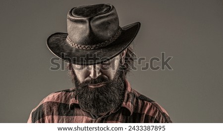 Cowboy style. Handsome young man adjusting his cowboy hat. Cowboys in hat. Handsome bearded macho. Man unshaven cowboys. American cowboy. Leather cowboy hat.