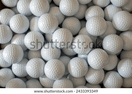 A large quantity of plain white golf balls in a box