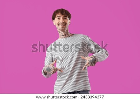 Young man pointing at his stomach on purple background
