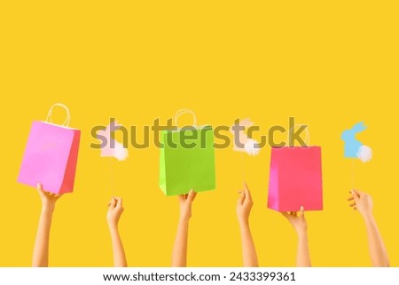 Women with shopping bags and Easter rabbits on yellow background. Online shopping