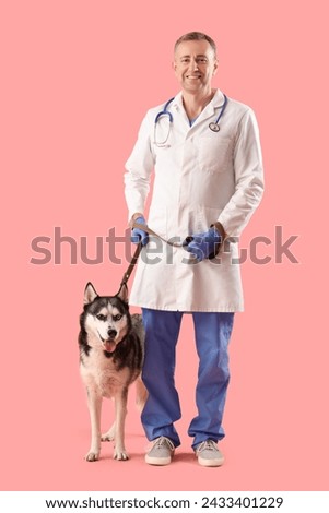 Male veterinarian with cute husky dog on pink background