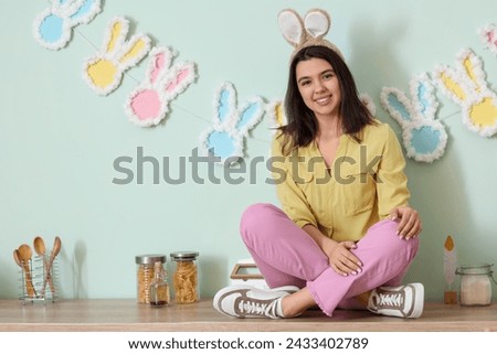 Beautiful young woman in bunny ears in kitchen. Easter celebration