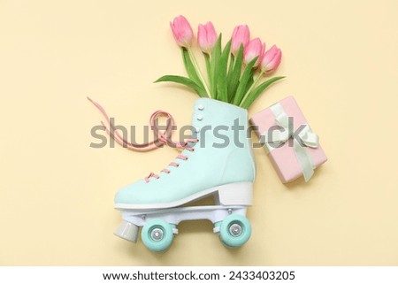 Composition with roller skate, gift box and tulip flowers on color background. International Women's Day