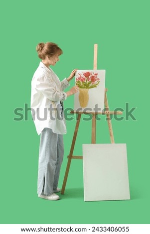 Female artist painting on canvas against green background