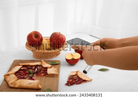 Female photographer taking photo of delicious apple pie in studio