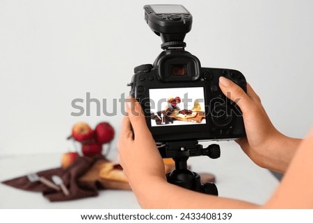 Female photographer taking photo of tasty apple pie in studio