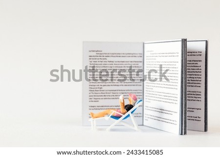 World Book Day concept, Miniature people A young woman reading a book alone against a white background