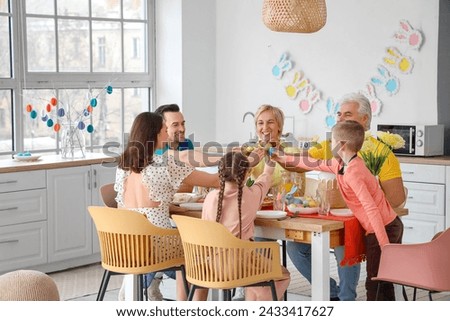 Happy family breaking Easter eggs at dinner in kitchen Royalty-Free Stock Photo #2433417627